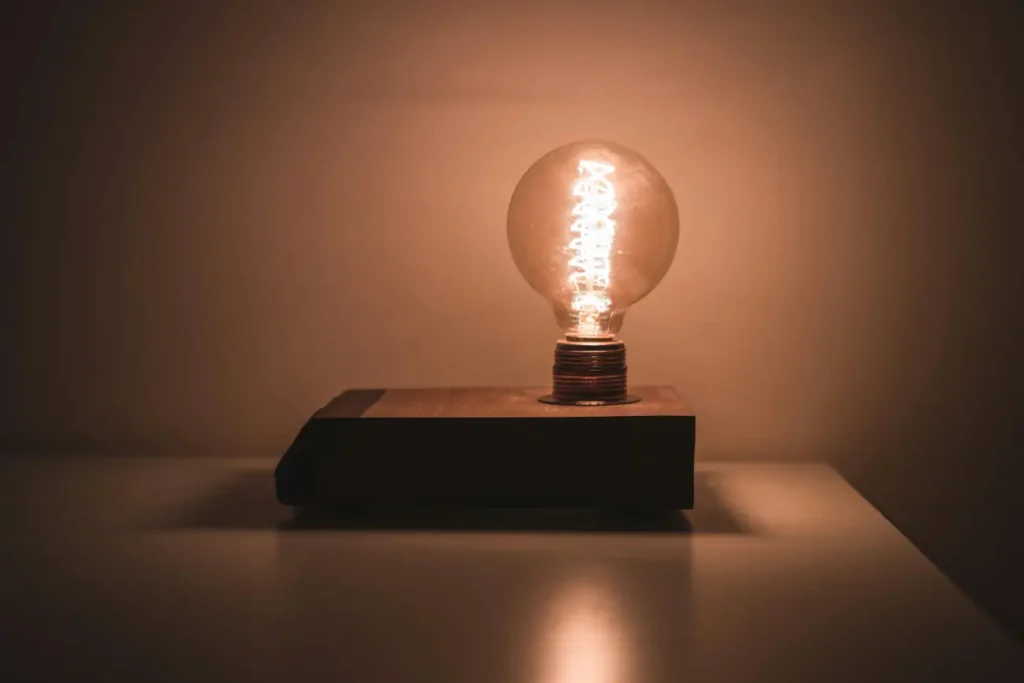 Glowing Edison bulb on a wooden base symbolizing a _bright idea._